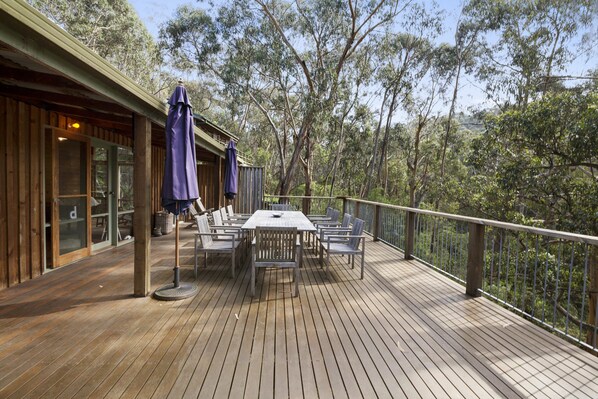 A wooden deck with a table and chairs, surrounded by trees.