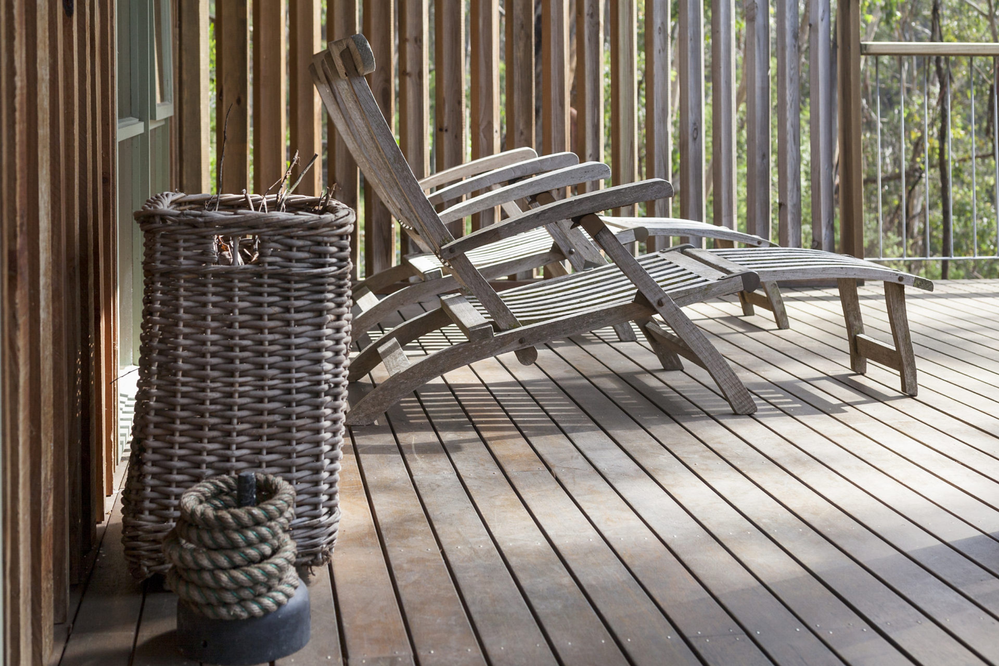Une terrasse en bois avec deux chaises longues et un panier en osier.