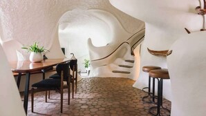 A dining area with a unique architectural design, featuring a curved wall and a staircase.