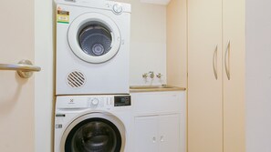 A laundry room with a stacked washer and dryer, a sink, and a cabinet. - Rocks Resort 4G - Currumbin Beachfront - Min. 3 night stays! (Currumbin)