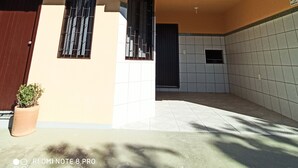 Una casa de dos pisos con un patio empedrado, una planta en maceta y una puerta a la vista.
