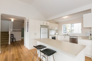 A modern kitchen with a central island, stainless steel appliances, and a view to the outside.