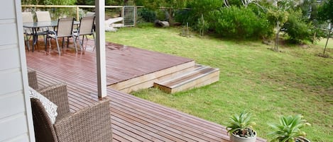 Una terraza de madera con mobiliario exterior y plantas en macetas.