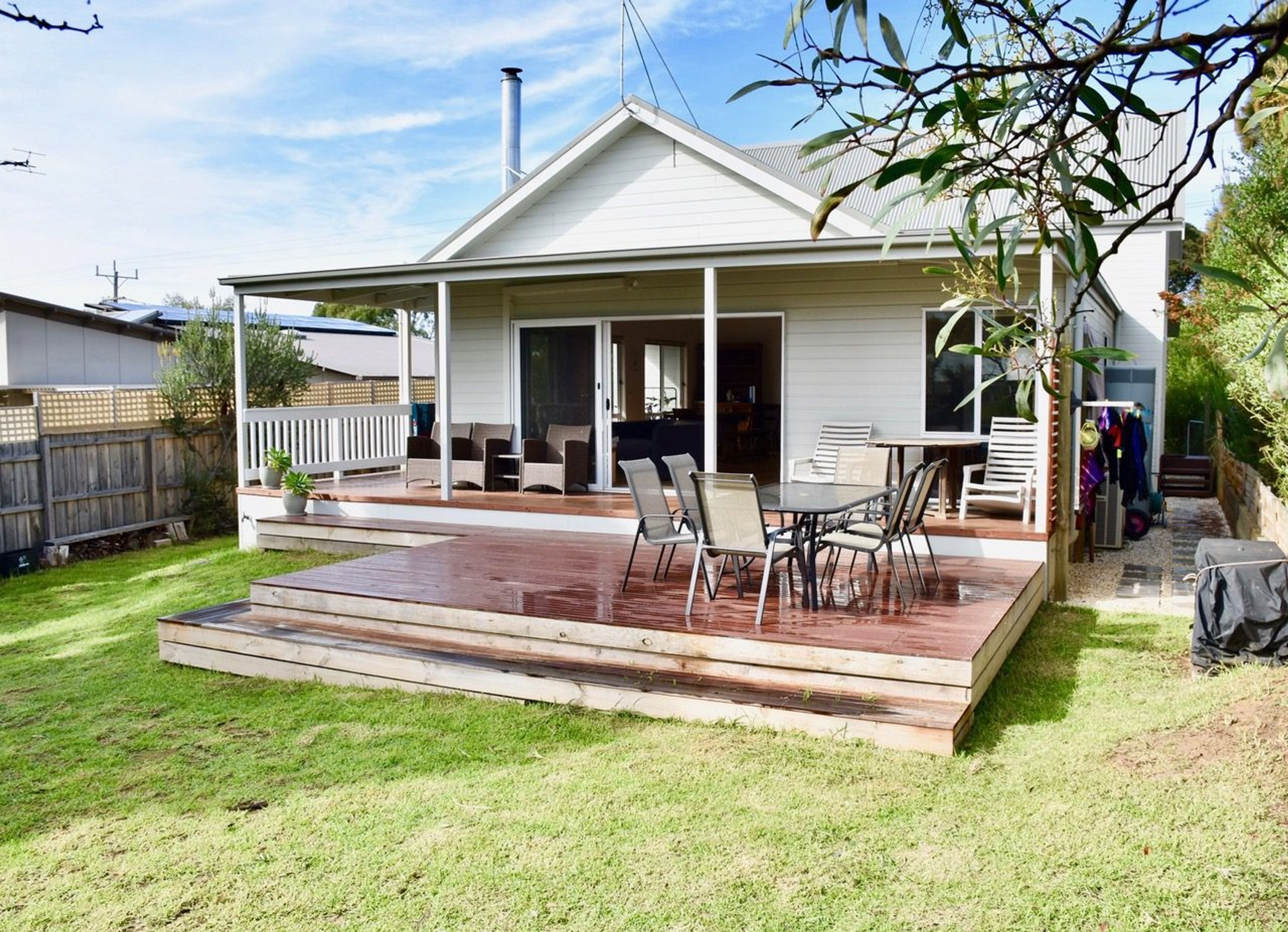 A house with a covered patio, a deck, and a lawn.