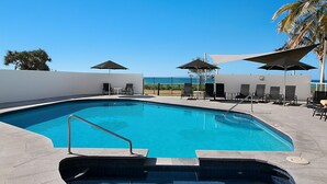 A swimming pool with a clear view of the ocean, surrounded by lounge chairs and umbrellas. - San Simeon 6 - Ground Floor, Absolute Beachfront at Tugun! (Tugun)