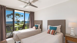 A hotel room with two beds, a ceiling fan, a view of the ocean, and a patio area with a table and chairs. - San Simeon 6 - Ground Floor, Absolute Beachfront at Tugun! (Tugun)