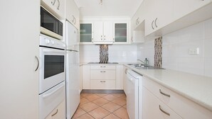 A modern kitchen with white cabinetry, a tiled backsplash, and a built-in oven. - San Simeon 6 - Ground Floor, Absolute Beachfront at Tugun! (Tugun)