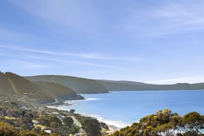 A coastal landscape with a clear view of the sea, hills, and a small settlement.