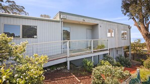 Un bâtiment à deux étages doté d’un balcon, entouré de différentes plantes et arbres.