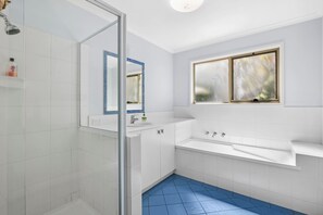 A modern bathroom with a glass shower enclosure, a white sink, and a bathtub.