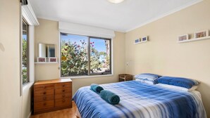A bedroom with a bed, dresser, window, and wall art.