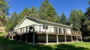 Een gelijkvloers huis met een overdekte veranda, omgeven door bomen en een heldere lucht.