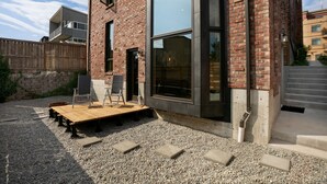 A modern building with a brick facade, large windows, and a wooden deck with steps leading to the entrance.