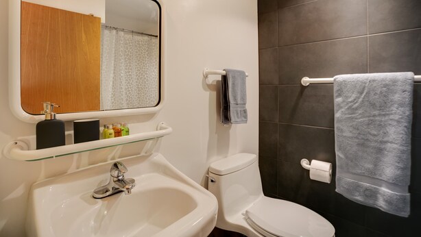 A bathroom with a white sink, a mirror, a toilet, and a towel rack.