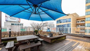 An outdoor deck with picnic tables and a large blue umbrella. - Residence Hotel LINE (Daejeon)