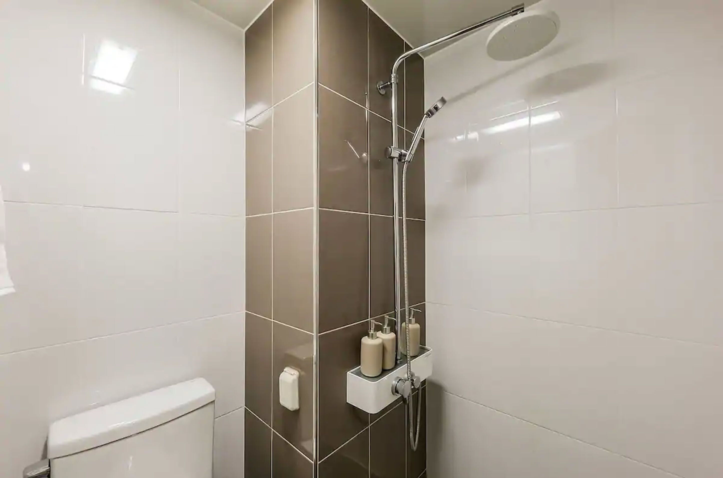 Moderni kylpyhuone, jossa on suihku, wc ja säilytystilaa.