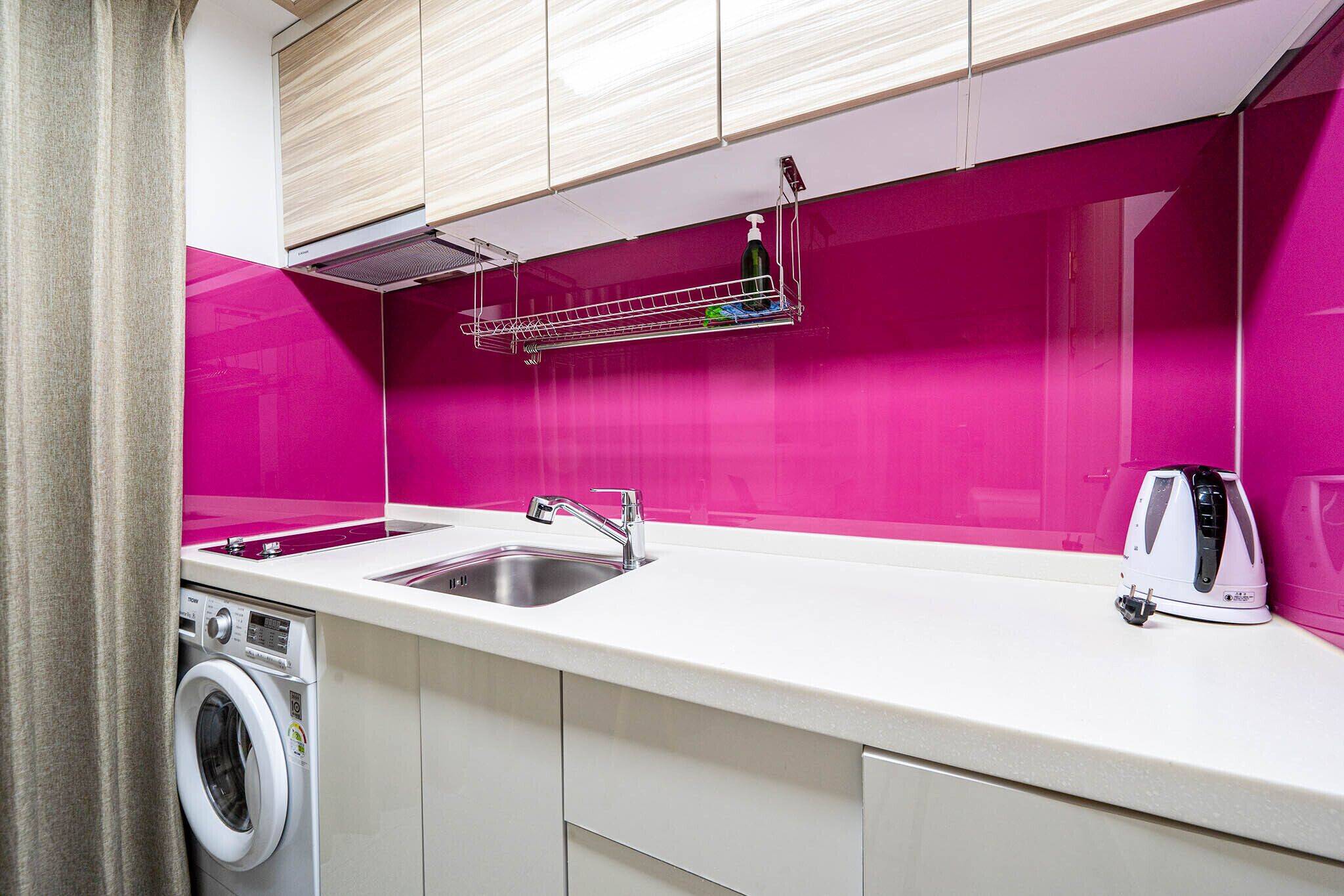Een kleine keuken met een wasmachine, een spoelbak en een waterkoker.