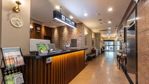 A hotel reception area with a modern design, including a reception desk, a clock, and a sign indicating the hotel name. - Residence Hotel LINE (Daejeon)