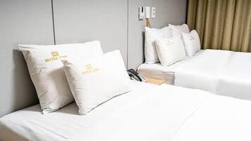 Een hotelkamer met twee bedden, elk voorzien van witte beddengoed en kussens met het logo van het hotel.