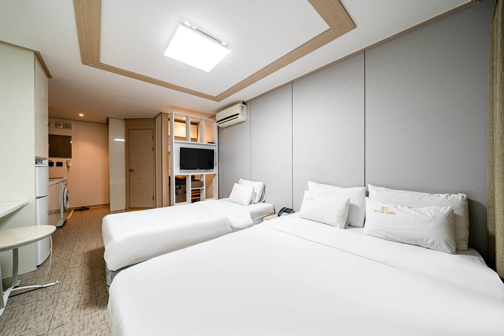 Habitación de hotel con dos camas, televisión, escritorio y minibar.