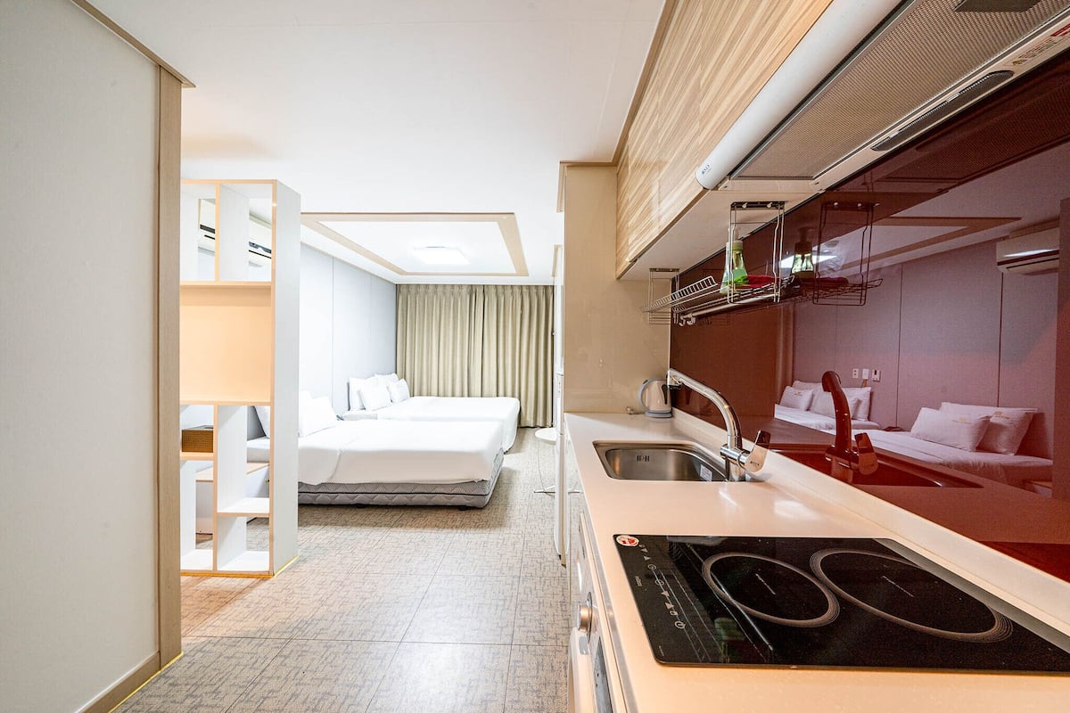 Une chambre d’hôtel de taille réduite, équipée d’une kitchenette, d’un lit et d’une salle de bain.