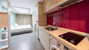 A compact hotel room with a kitchenette, a bed, and a washing machine. - Residence Hotel LINE (Daejeon)