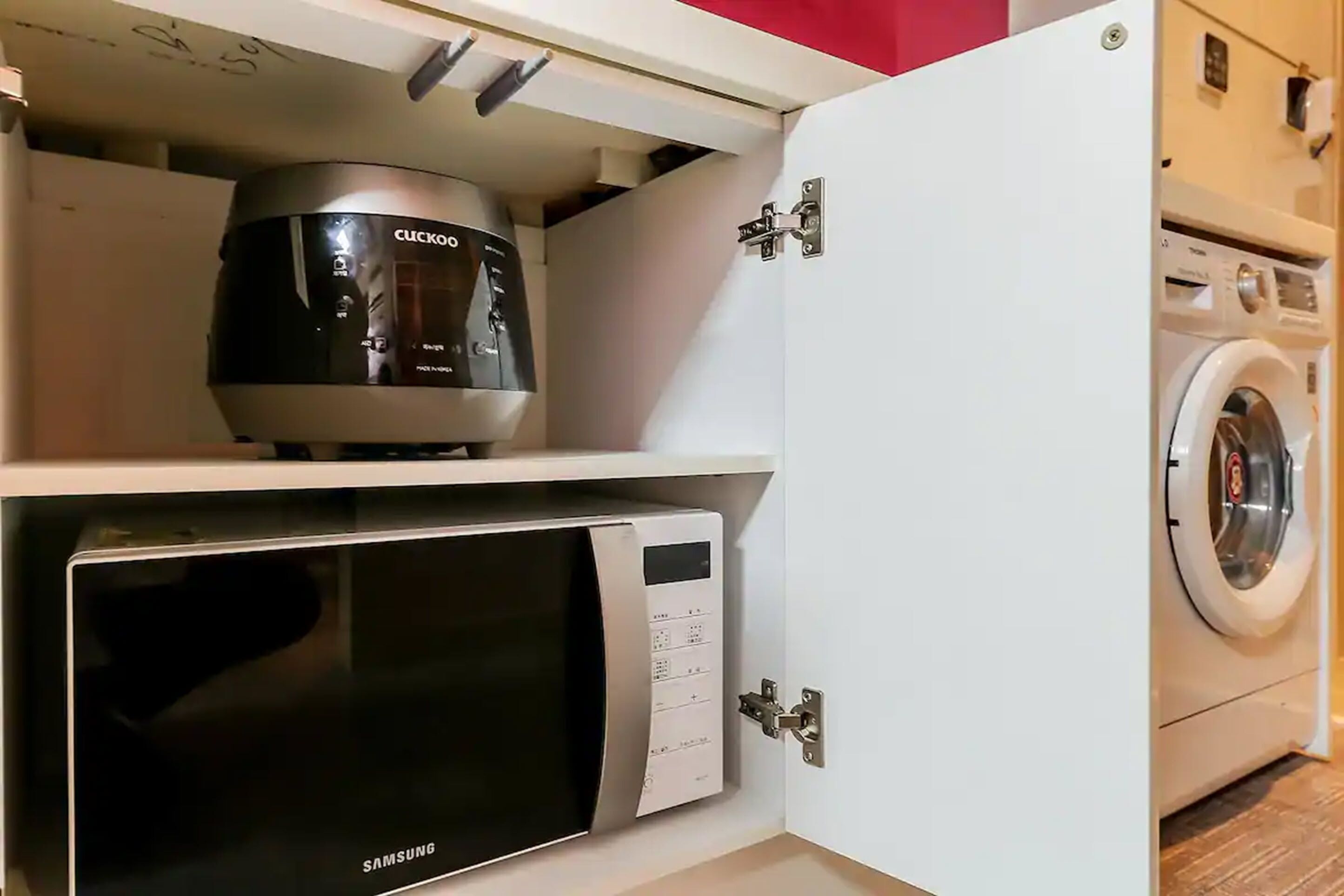 A compact kitchen with a microwave, a coffee maker, and a washing machine.