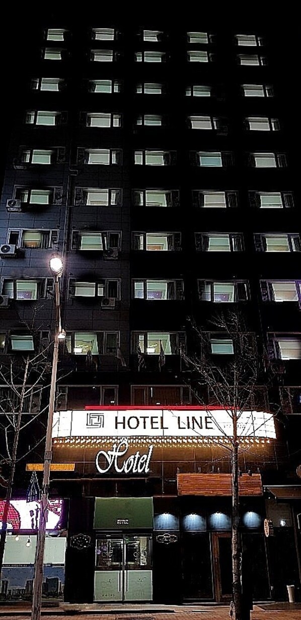 Un edificio de hotel de varios pisos con un llamativo letrero que dice 'HOTEL LINE' en la entrada.