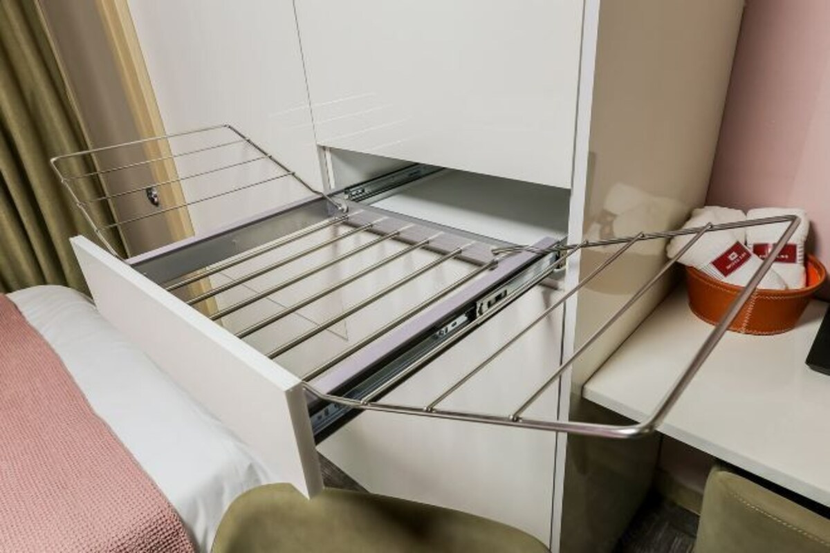 Una habitación compacta con cama, escritorio y silla, y un tendedero integrado.