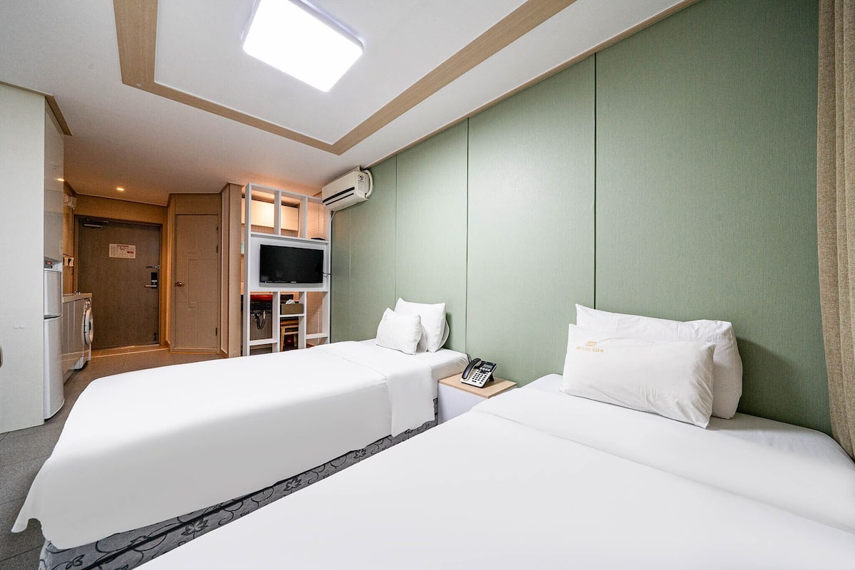 Une chambre d’hôtel avec deux lits, une télévision, un téléphone et une kitchenette.