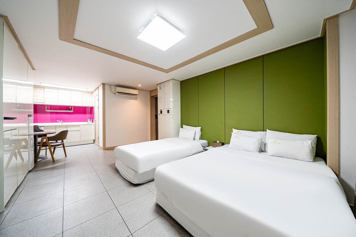 Une chambre d’hôtel avec deux lits, une kitchenette et un coin repas.