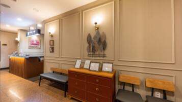 A reception area with a counter, a bench, a wooden cabinet with drawers, and wall-mounted light fixtures.