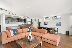 Un salon moderne avec un canapé d’angle, une table basse en bois et un coin repas comprenant une table et des chaises.