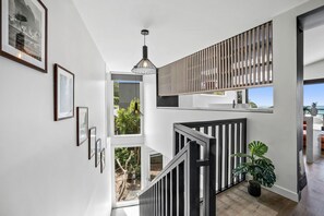 A modern interior with a staircase, framed artwork, and a hanging light fixture.