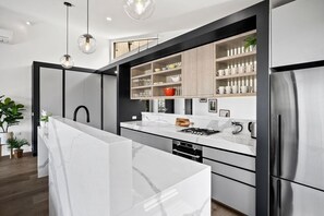 A modern kitchen with a marble countertop, stainless steel appliances, and wooden cabinets.