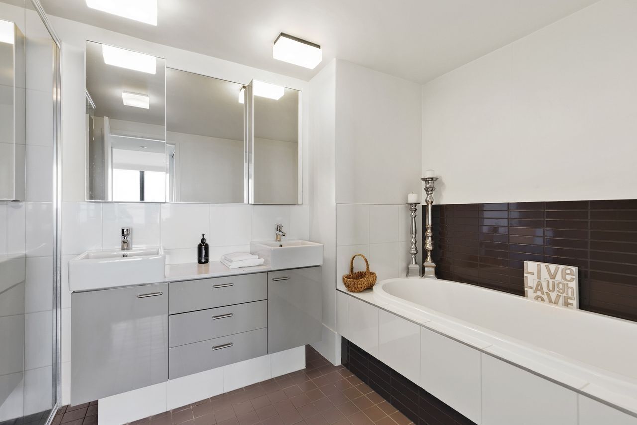 Une salle de bain moderne avec deux lavabos, un grand miroir, une baignoire et un porte-serviettes.