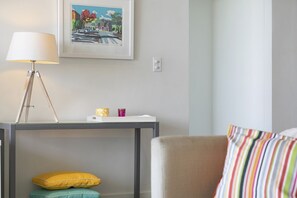 A room with a bed, a bedside table with a lamp, a framed picture on the wall, and a chair with a striped pillow. - Lorne Chalet Apartment 42 (Lorne)