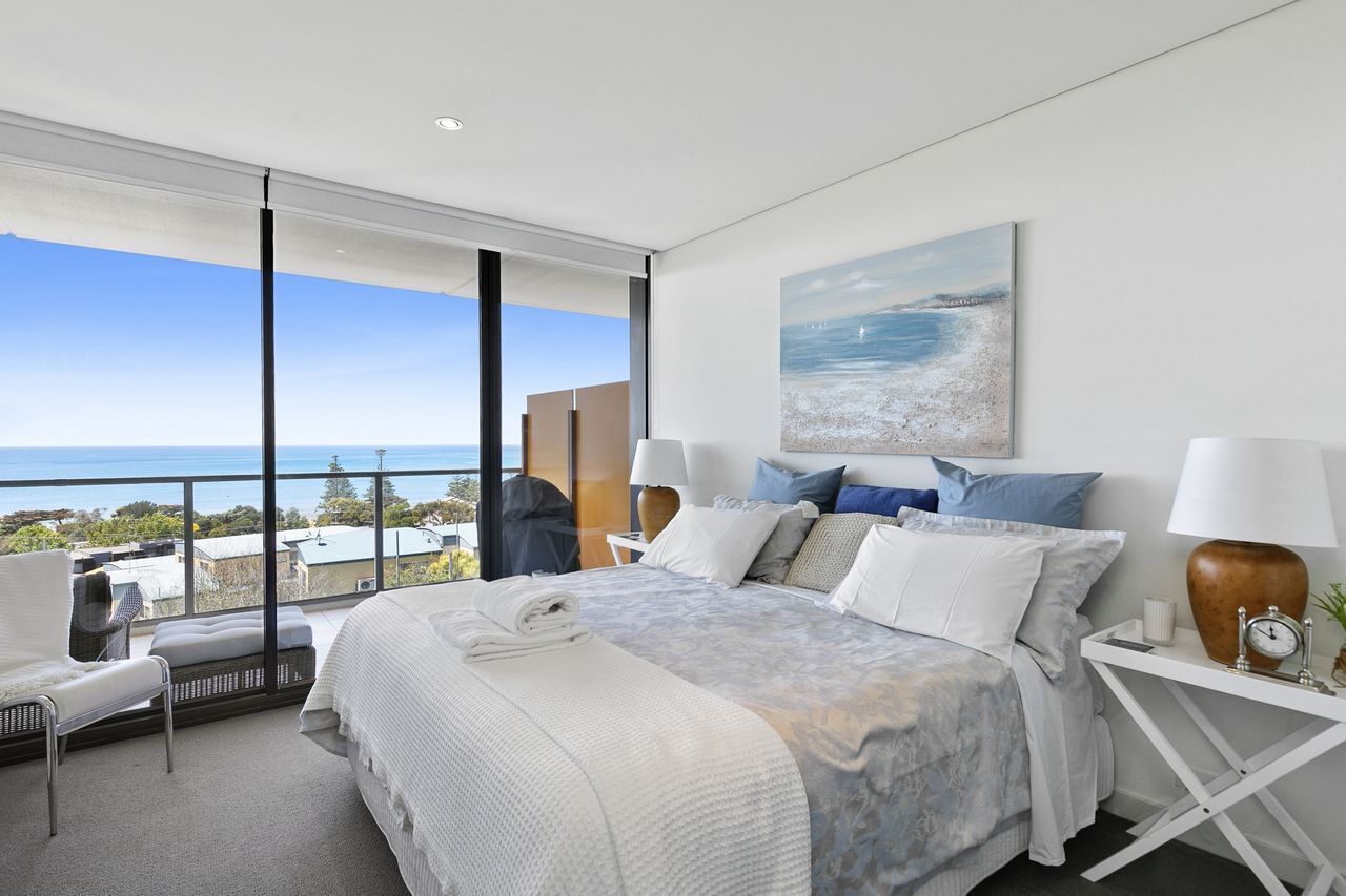 Ein modernes Hotelzimmer mit einem großen Bett, Meerblick und einem Balkon mit einem Sessel.