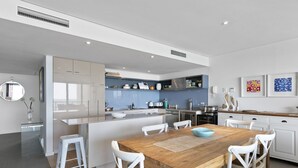 Een moderne keuken met witte kasten, een houten eettafel en een centraal eiland.