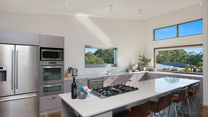 Eine moderne Küche mit Edelstahlgeräten, einer großen Kochinsel und Blick ins Freie.