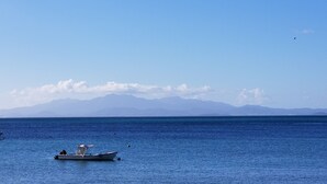 Ein Boot auf ruhigem, blauem Wasser, im Hintergrund Berge.
