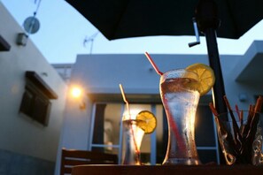 A bar setting with two glasses of iced drinks, one with a lemon slice and a straw, and a glass with straws and a lemon slice. - Sun Flower (Onna)