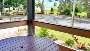 Una terraza de madera con vistas a una carretera y vegetación.