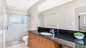 A modern bathroom with a glass shower enclosure, a white toilet, and a black granite countertop with a sink and mirror. - Aqua Solai 9 - Absolute Beachfront Tugun - Min. 3 night stays - Linen Provided (Tugun)
