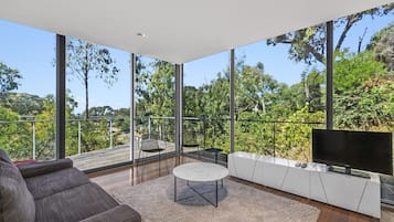 A modern living room with a large window, a flat-screen TV, and a sofa.