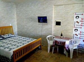 A small room with a bed, a TV, a table with a bottle, and a poster on the wall. - Itaipuaçu Apartments Cajueiros I and II (Entire premises with privacy) (Maricá)