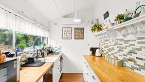 A modern kitchen with wooden countertops, white cabinetry, and a tiled backsplash. - Luxury Heritage Cottage with Harbour Views in Albany (Albany)