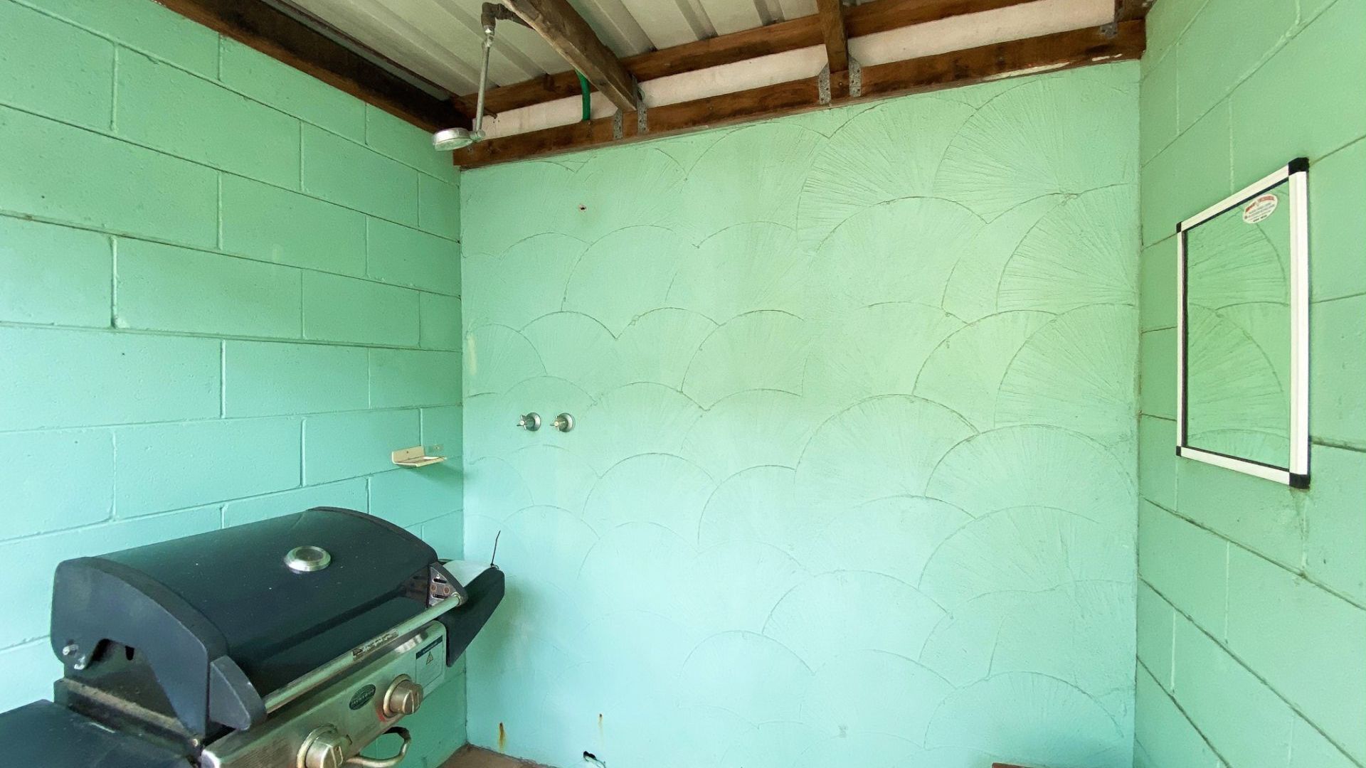 Une petite pièce aux murs de couleur turquoise, avec un plafond en bois et une grille noire.