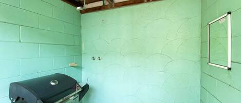 Une petite pièce aux murs de couleur turquoise, avec un plafond en bois et une grille noire.
