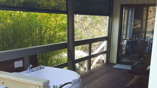 A covered outdoor deck with a hot tub, wooden flooring, and a view of greenery. - "Get away from the world for a while" (Macclesfield)